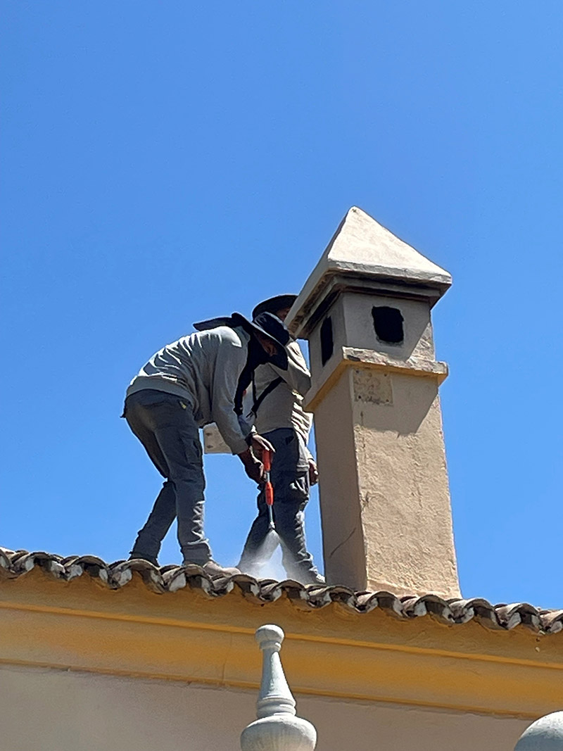 cleaning roof chimney roofers on a clay tiled roof cleaning around the chimney area