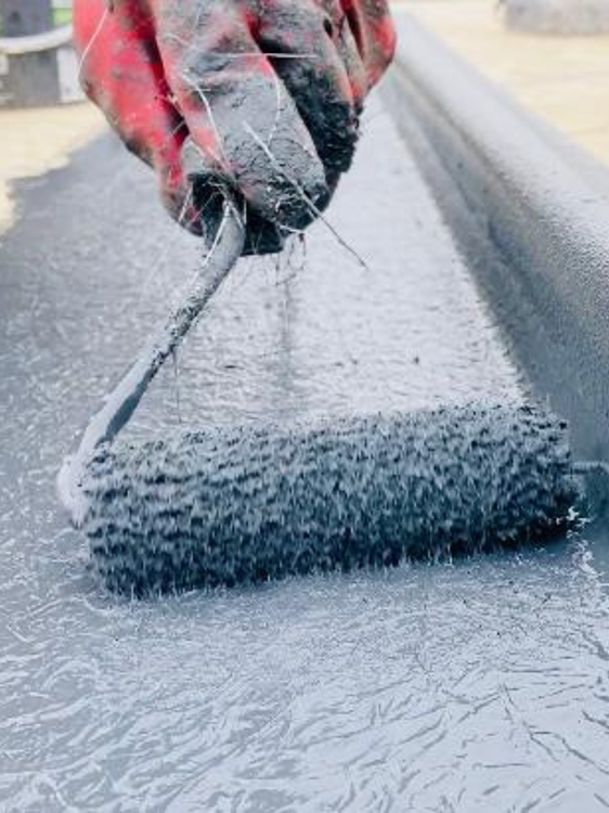 roller roller being used to apply waterproofing to a roof