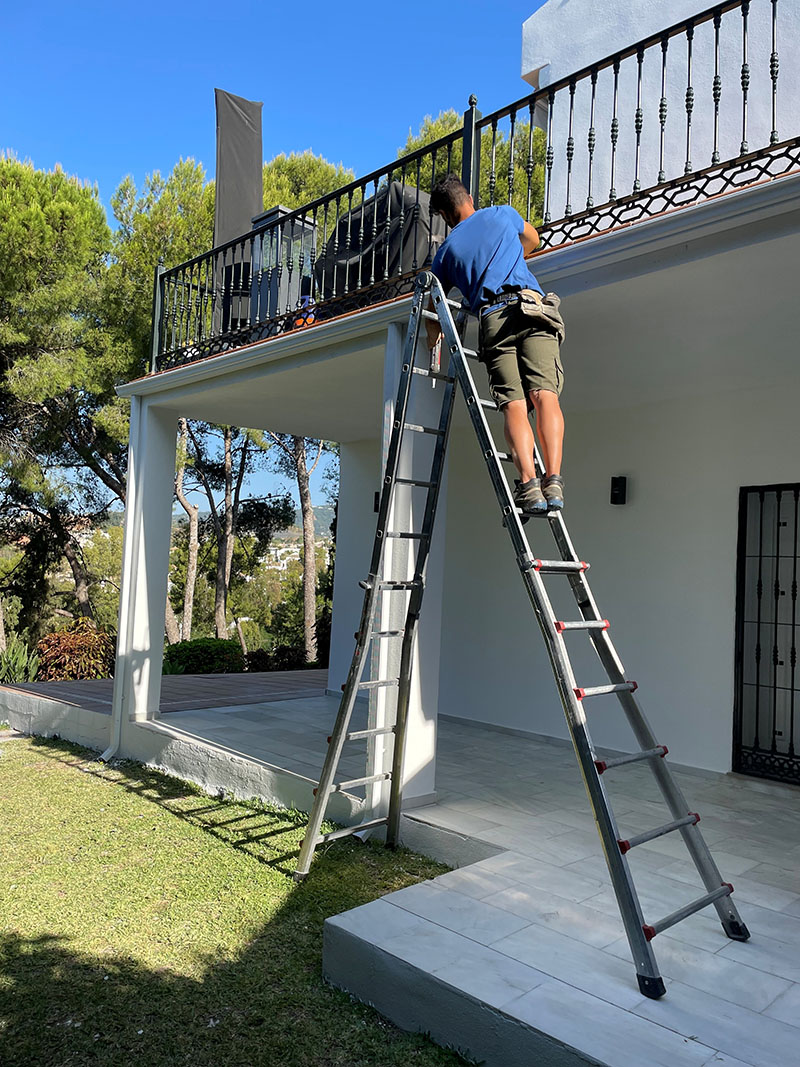 roofer-installing-guttering roofer up a step ladder fitting guttering on the costa del sol