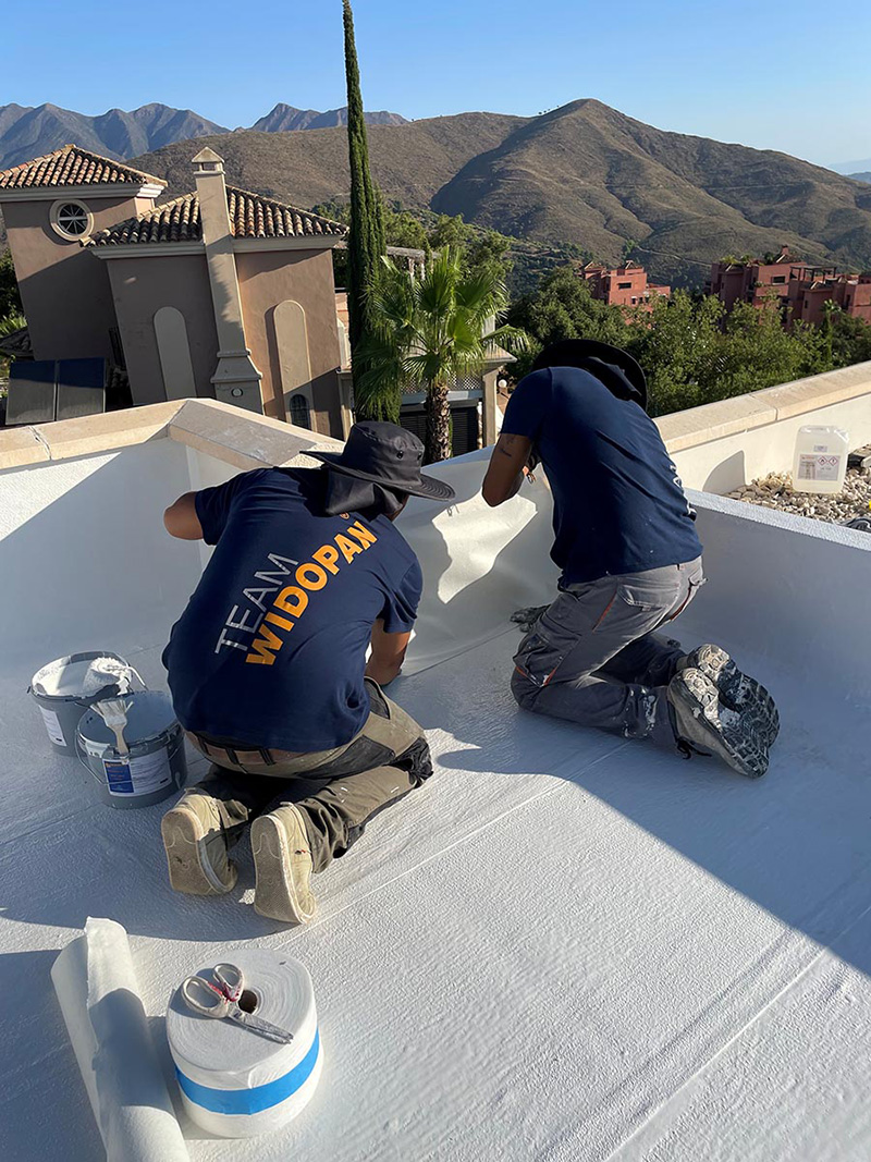 widopan being applied to a roof in Marbella two roofers on a flat roof applying widopan